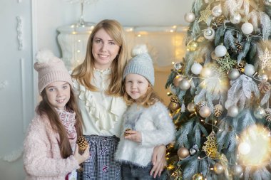 Şirin harika sarışın anne anne iki kız kızı xmas ağacı ile şeker dolu oyuncak şık elbiseler yakın yeni yıl Noel Kutlamaları