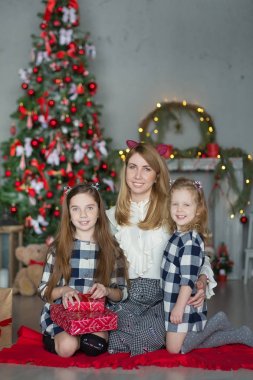 Şirin harika sarışın anne anne iki kız kızı xmas ağacı ile şeker dolu oyuncak şık elbiseler yakın yeni yıl Noel Kutlamaları