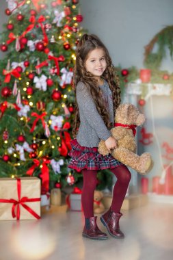 Çocuk Noel ağacı ve evde şömine yakın hediye kutusu ile küçük kız