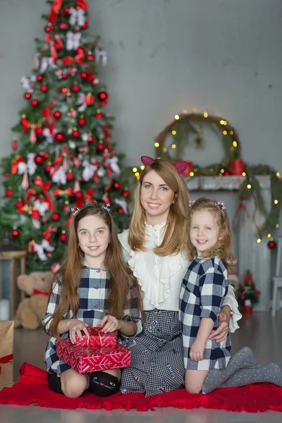Şirin harika sarışın anne anne iki kız kızı xmas ağacı ile şeker dolu oyuncak şık elbiseler yakın yeni yıl Noel Kutlamaları