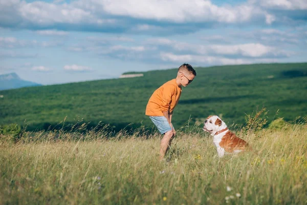 Niño corriendo en el campo con el perro toro en las montañas — Foto de Stock