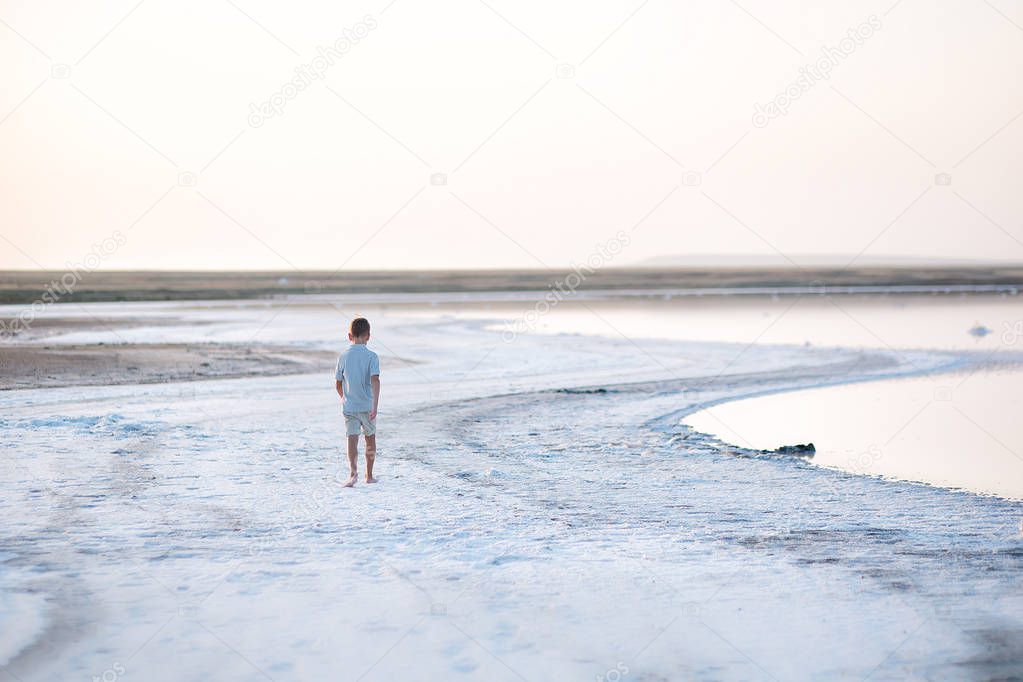 A boy walks along the shore of the lake. A Salt lake shore. A Salt Lake.
