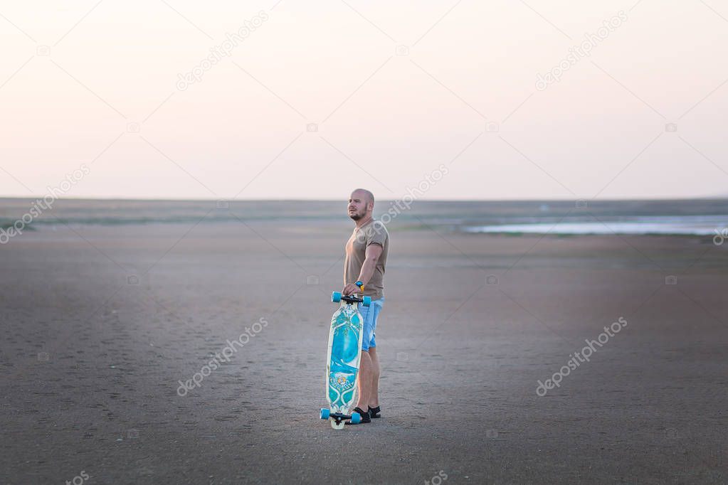 A man walks along the shore of the lake with skate board. A Salt lake shore. A Salt Lake.