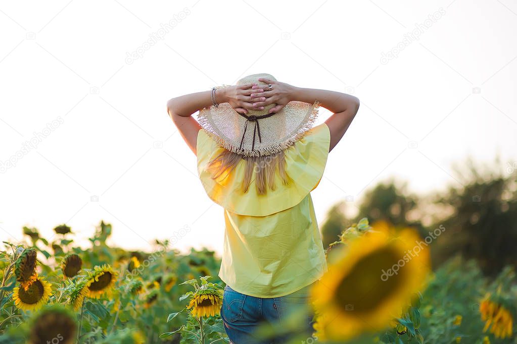 Young fashion woman with a sun flowers and in stylish hat and blue jeans shorts