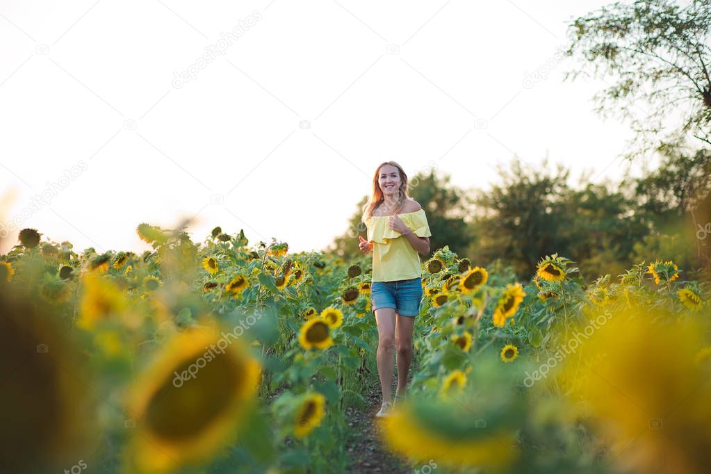 Young fashion woman with a sun flowers and in stylish hat and blue jeans shorts