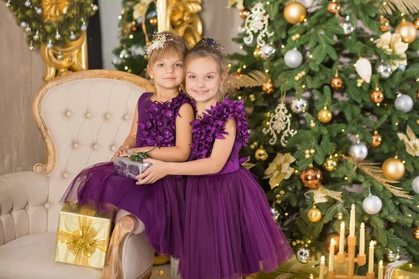 Happy Christmas grappige kinderen kind meisje genieten van Nieuwjaar decoratie studio met boom spiegel en bank stoel gekleed in casual luchtige jurken presenteert — Stockfoto