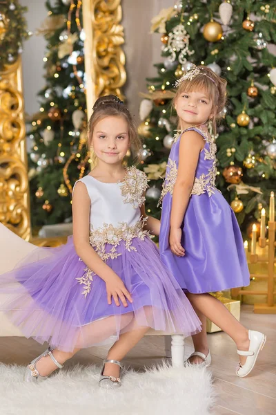 Happy Christmas grappige kinderen kind meisje genieten van Nieuwjaar decoratie studio met boom spiegel en bank stoel gekleed in casual luchtige jurken presenteert — Stockfoto
