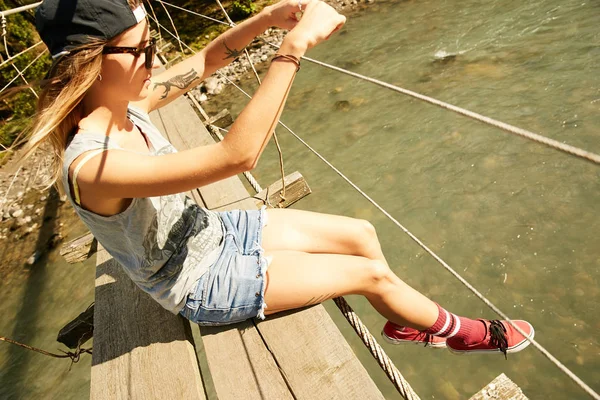 Kvinnan sitter på hängande footbridge — Stockfoto