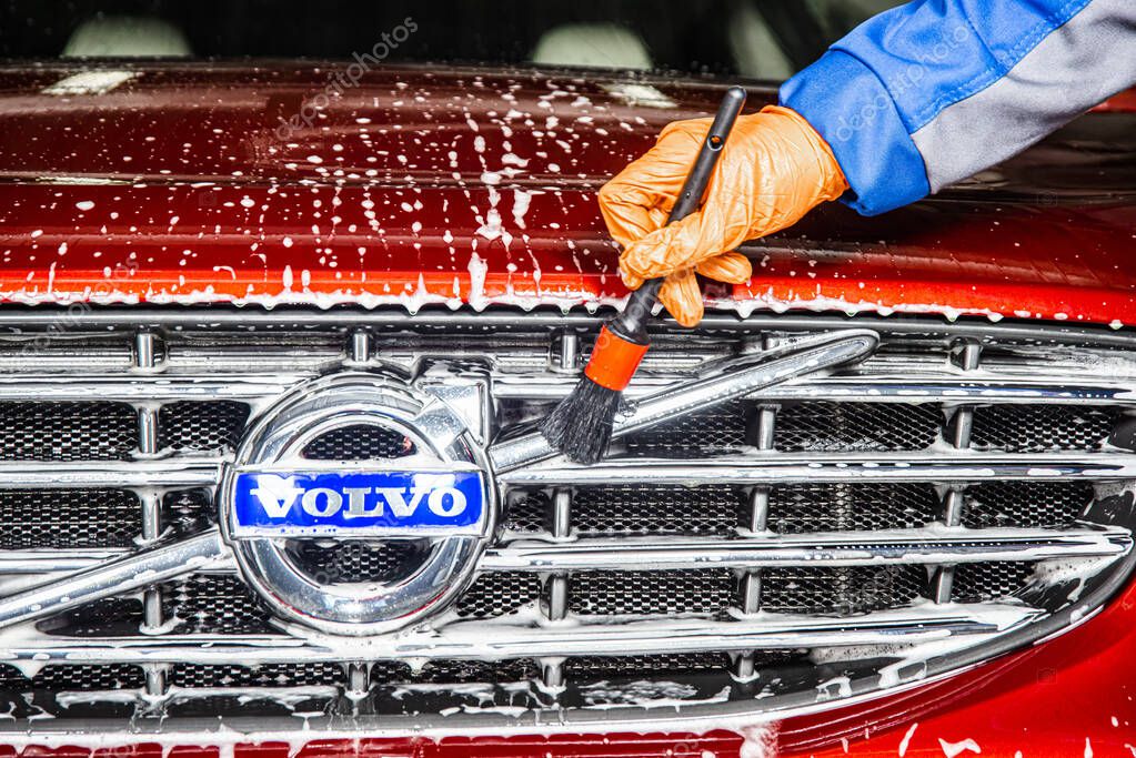 Sankt-Petersburg, Russia - April 23 2017: Close-up of a volvo cars manufacturing logo on the modern car while washing in the detaing workshop with foam soap and worker hand with a brush