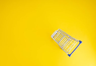 Sarı arka planda boş alışveriş arabası