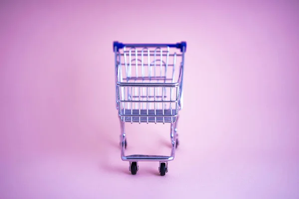 Leere Einkaufswagen vor rosa Hintergrund — Stockfoto
