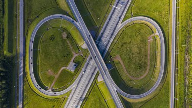 Şehirdeki otoyolun havadan görüntüsü. Arabalar üst geçitten geçiyor. Otoyol trafiği ile kesişir. Otobanın havadan çekilmiş kuş bakışı fotoğrafı. Çevre yolu. Yol ayrımları. Araba geçiyor. Yukarıdan üst görünüm.