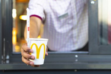 Sankt-Petersburg Rusya - 21 Temmuz 2019: McDonalds çalışanı Coca-Cola bardağı tutuyor. Elinde kamışla McDonalds 'ın arabasının camından içeri dalan bir kağıt bardakla....