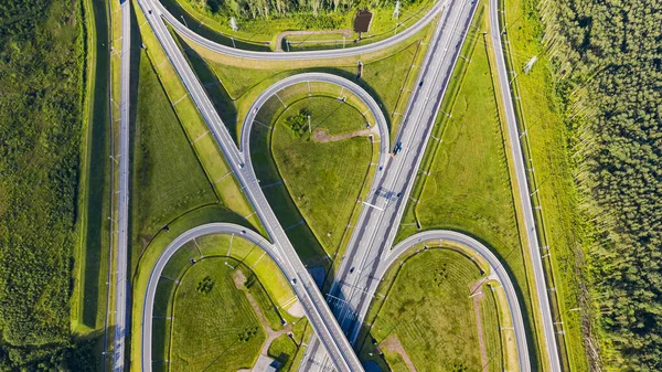 Aerial view of highway in city. Cars crossing interchange overpass. Highway interchange with traffic. Aerial bird\'s eye photo of highway. Expressway. Road junctions. Car passing. Top view from above.