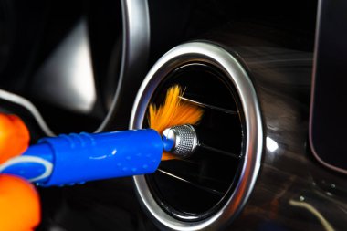 Arabanın iç kısımlarındaki tozları fırçalamak torpido gözünün kontrol paneli. Elbise ve fırçayla araba temizleyen bir adam. Araba tamiri. İşçi temizliği. Temizlenecek fırça ve temizlik çözeltisi