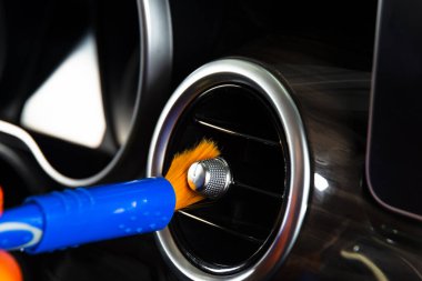 Arabanın iç kısımlarındaki tozları fırçalamak torpido gözünün kontrol paneli. Elbise ve fırçayla araba temizleyen bir adam. Araba tamiri. İşçi temizliği. Temizlenecek fırça ve temizlik çözeltisi