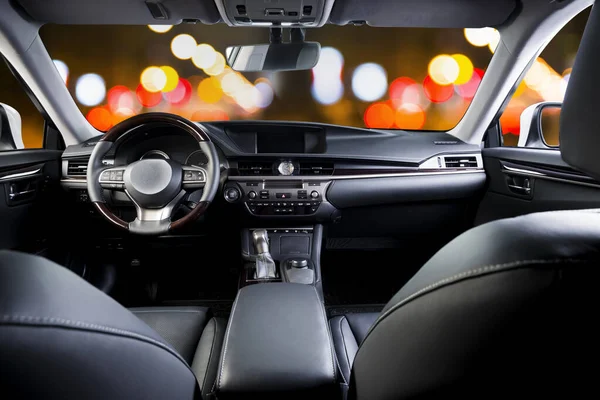 Dark luxury car Interior - steering wheel, shift lever and dashboard. Car inside. Blurred night city