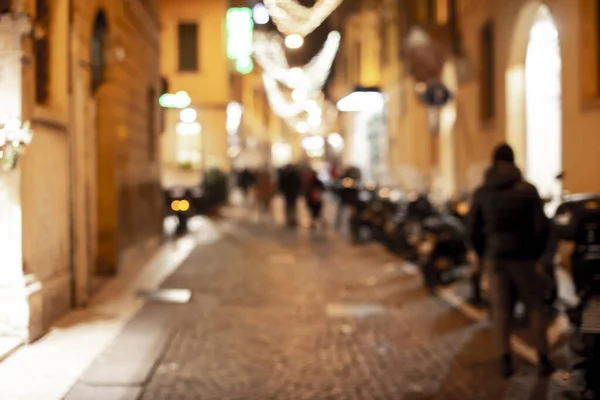 People rush on the street. Blurred crowd of different people are walking in the city. Defocused background of city life. Evening with lights.