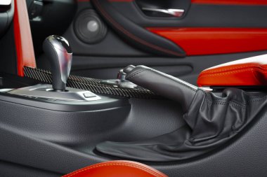 İçerideki kırmızı delikli lüks deri araba. Direksiyon, vites kolu ve gösterge paneli.. 