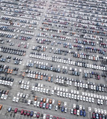 Otoparkta bir sürü yeni araba var. Farklı renklerde arabalarla dolu büyük otoparkın havadan görünüşü