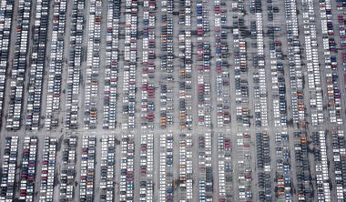 Otoparkta bir sürü yeni araba var. Farklı renklerde arabalarla dolu büyük otoparkın havadan görünüşü