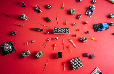 Kırmızı arkaplan üzerinde mikro elektronik arduino DIY bileşenleri, üst görünüm, kopyalama alanı. Mikro kontrolörler, panolar, sensörler, kollar, kontrolörler.