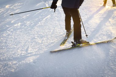 Günbatımında uzman kayakçılar, karda geziyorlar.