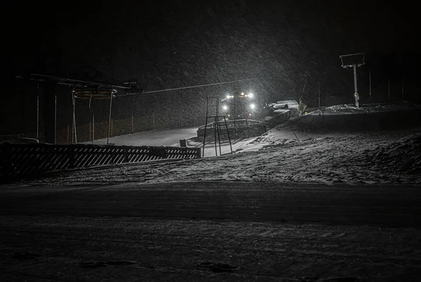 雪猫与前灯准备一个斜坡在山上的滑雪场与降雪 — 图库照片