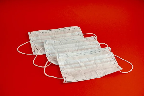 Set of three White medical masks. Medical protective masks over red background. Healthcare and medical concept. Protective face mask or medical mask. Protective shielding bandage