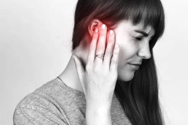 La joven tiene dolor de oído. chica que sufre de otitis. Blanco y negro con acento rojo — Foto de Stock