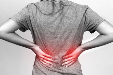  Güzel kadın sırt ağrısı ayakta gri arka plan üzerinde uğrar. 