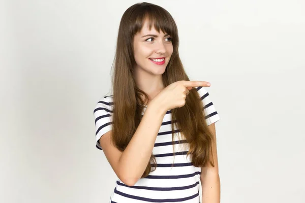 Glückliche Frau zeigt Finger weg über grauem Hintergrund. — Stockfoto