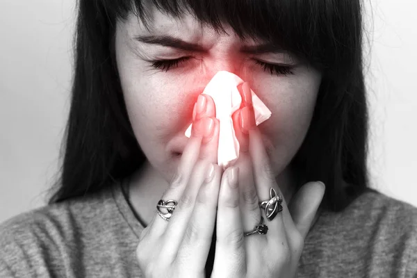 Retrato de una mujer bonita que tiene gripe. Chica sonándose la nariz. Blanco y negro con acento rojo . —  Fotos de Stock