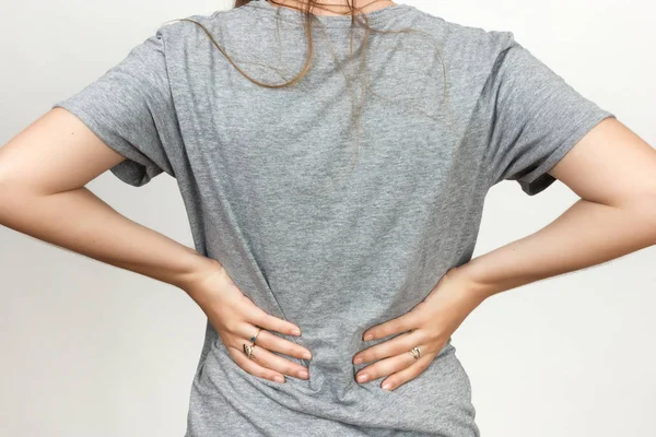 Hübsche Frau leidet unter Rückenschmerzen vor grauem Hintergrund — Stockfoto