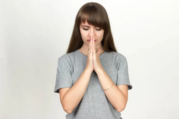 Frau betet vor grauem Hintergrund. — Stockfoto