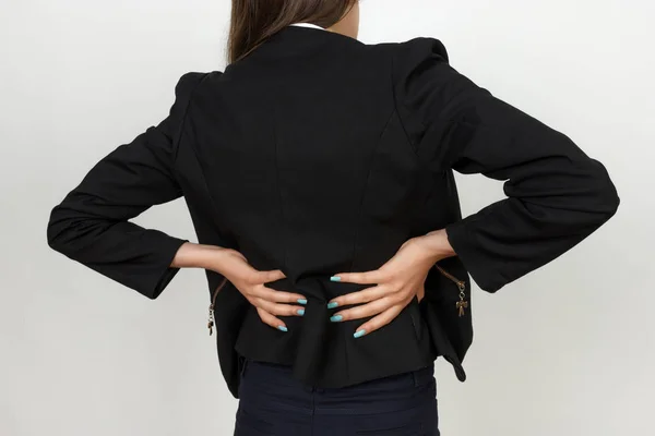 Uma jovem empresária sofre de dores nas costas. Conceito de dor close-up — Fotografia de Stock