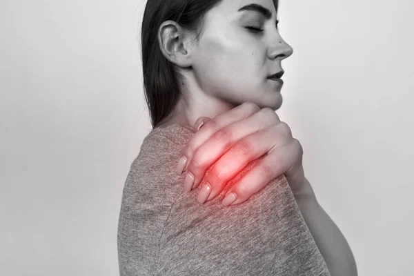 Junge Frau mit Schulterschmerzen. Schwarz-weiß mit rotem Akzent. Schmerzkonzept hautnah — Stockfoto