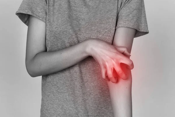 Girl in grey shirt scratching her arm. Scabies. Scratch the hand. Black and white with red accent — Stock Photo, Image