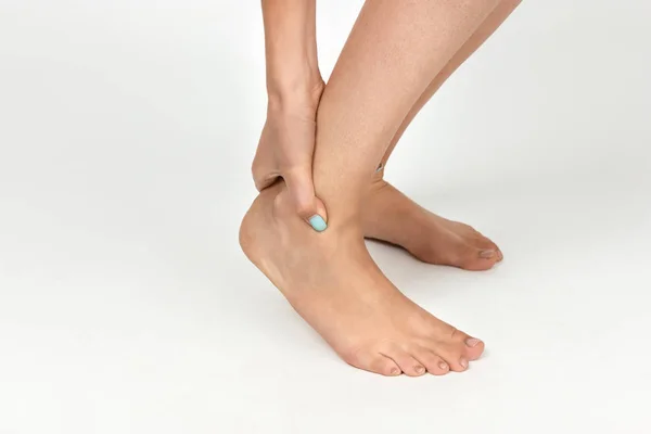 Mulher mão segurando seu belo pé saudável e massageando tornozelo na área de dor. Conceito de dor close-up — Fotografia de Stock