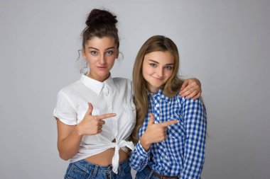 Mutlu gösterilen iki genç kız kardeş uzak gri arka plan üzerinde parmak. Kameraya bakarak