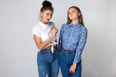 İki genç kız kardeşi ayakta ve gri arka plan üzerinde müzik kulaklık