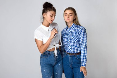 İki genç kız kardeşi ayakta ve gri arka plan üzerinde müzik kulaklık