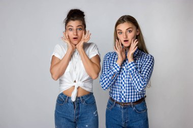 Gri arka plan üzerinde iki sürpriz genç kız kardeş