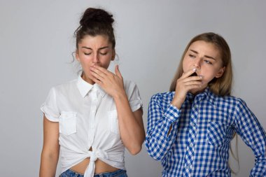 Gri bir arka plan üzerinde iki yorgun genç kız kardeş.