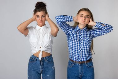 Gri arka plan üzerinde duran onların kulaklarını kapsayan iki genç kız portresi