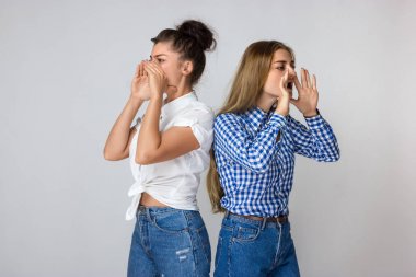 Çığlık atan iki genç kız portresi iki eli onu yüz ayakta gri arka plan üzerinde koymak