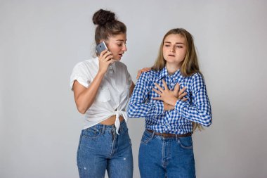 Güzel kadın kalp krizi ya da kırık kalp ile kız kardeşi gri arka plan üzerinde duran bir doktor çağırır.