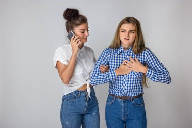 Güzel kadın kalp krizi ya da kırık kalp ile kız kardeşi gri arka plan üzerinde duran bir doktor çağırır.