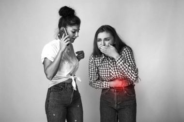 Mide sorunları olan güzel bir kadın portresi kız kardeşi bir doktor çağırır. ve gri arka plan üzerinde ayakta. Siyah ve beyaz ile kırmızı vurgu.