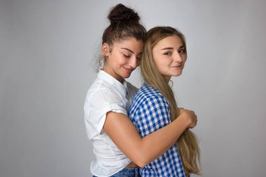 Stüdyo portre genç ve mutlu Sisters gri arka plan üzerinde.